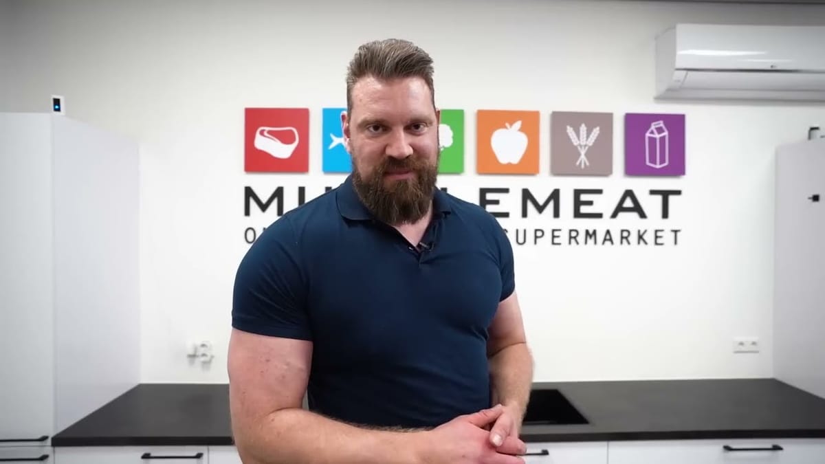 Olivier Richters in a navy polo at Muscle Meat, in front of the company logo