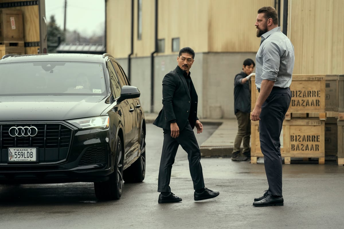 Reacher season 3: Brian Tee as Quinn walks past Paulie outside a warehouse